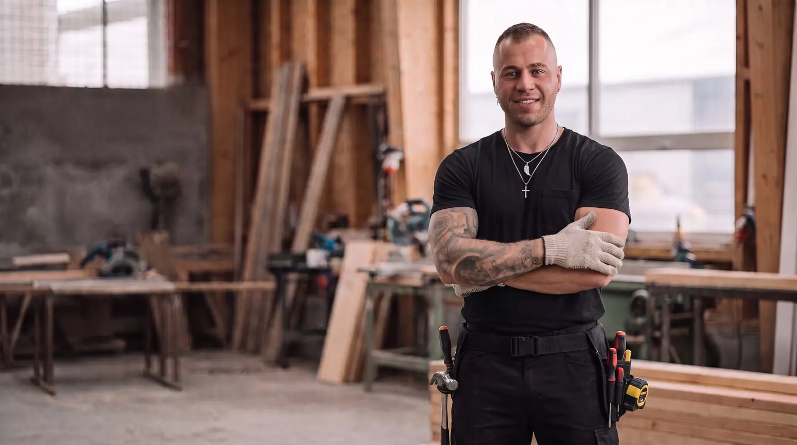 Alex the handyman standing in his workshop with a tool belt