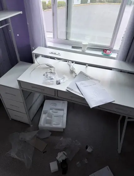 Assembled white desk with drawers by a window